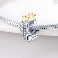 Charm lettre J en argent avec couronne dorée et petits strass, style élégant et raffiné.
