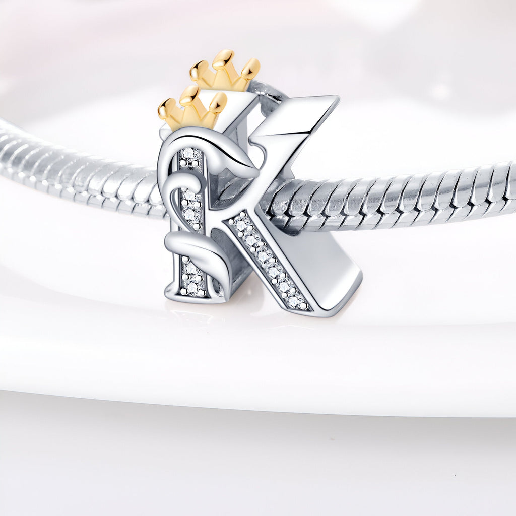 Charm lettre K en argent orné de cristaux avec couronne dorée, monté sur bracelet serpent argenté.