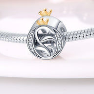 Charm lettre O argenté avec couronne dorée et détails feuille, serti de petits cristaux blancs.