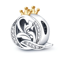 Charm lettre Q en argent avec couronne dorée et détails floraux ornés de pierres blanches brillantes.