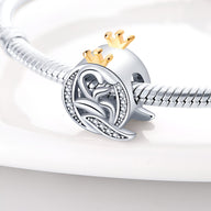 Charm lettre Q en argent avec couronne dorée et détails ajourés sur bracelet serpent en métal brillant.