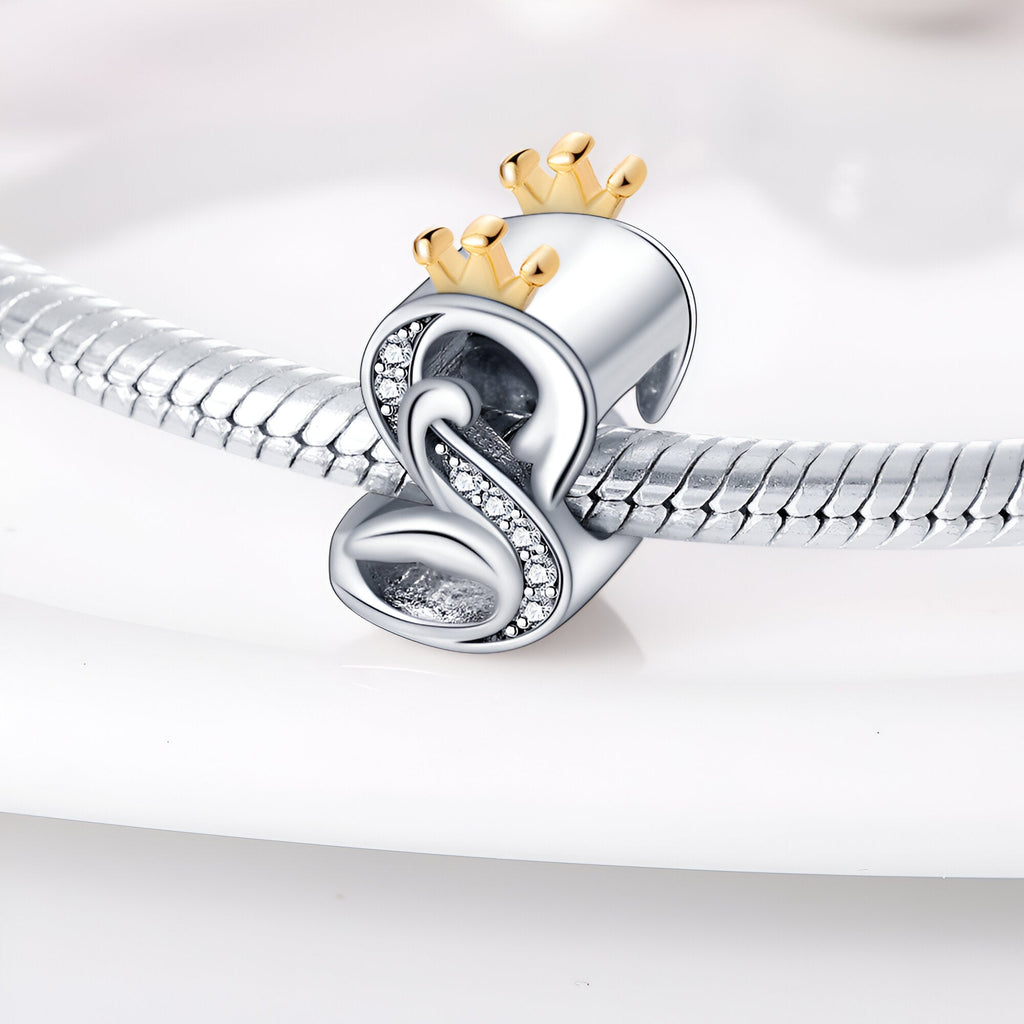 Charm lettre S en argent avec couronne dorée et détails en cristaux sur bracelet serpent en argent.