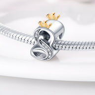 Charm lettre S en argent avec couronne dorée et détails en cristaux sur bracelet serpent en argent.