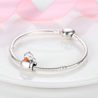 Bracelet argenté serpent avec charm canard en émail orange et blanc.