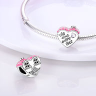 Charm en argent en forme de maison avec toit rose et détails gravés, monté sur bracelet en argent.