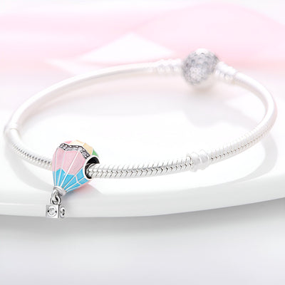 Charm montgolfière en argent avec émail rose et bleu sur bracelet serpent argenté.