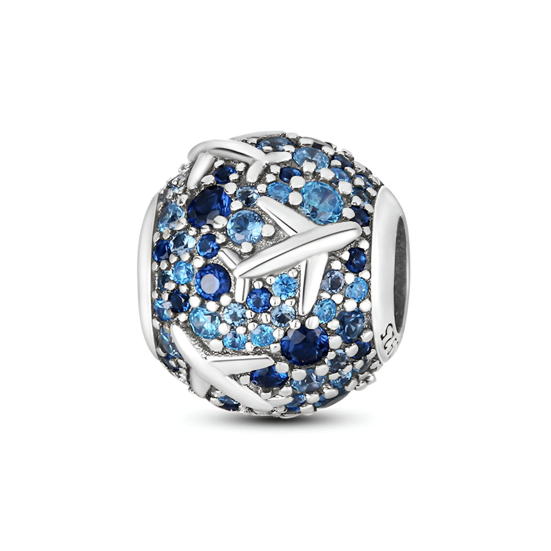 Charm sphérique en argent avec motifs d’avions et pierres bleues de différentes nuances.