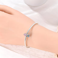 Bracelet fin argenté avec charm multiple fleurs en émail rose et violet.