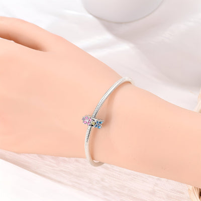 Bracelet fin argenté avec charm multiple fleurs en émail rose et violet.