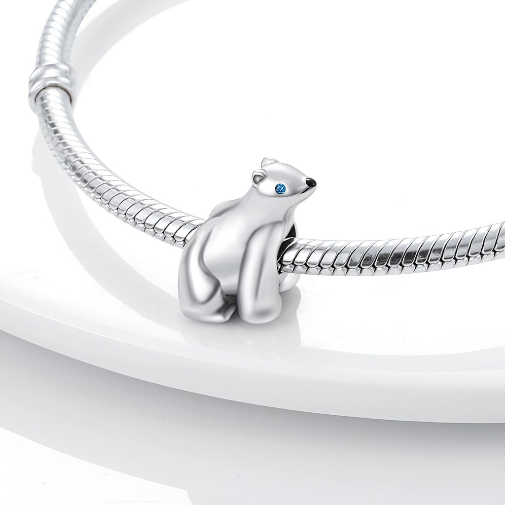 Charm ours polaire en argent avec yeux bleus, posé sur bracelet serpent argenté.