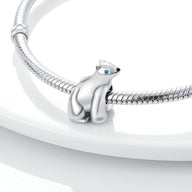 Charm ours polaire en argent avec yeux bleus, posé sur bracelet serpent argenté.