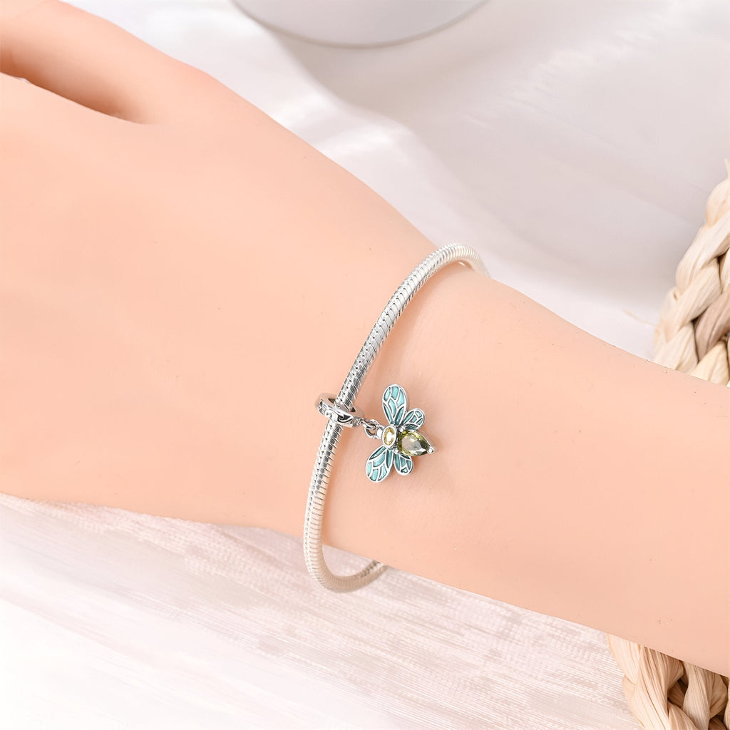 Bracelet argenté fin avec pendentif abeille orné de cristaux bleus sur poignet féminin.