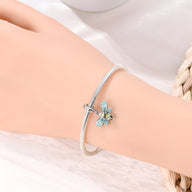 Bracelet argenté fin avec pendentif abeille orné de cristaux bleus sur poignet féminin.