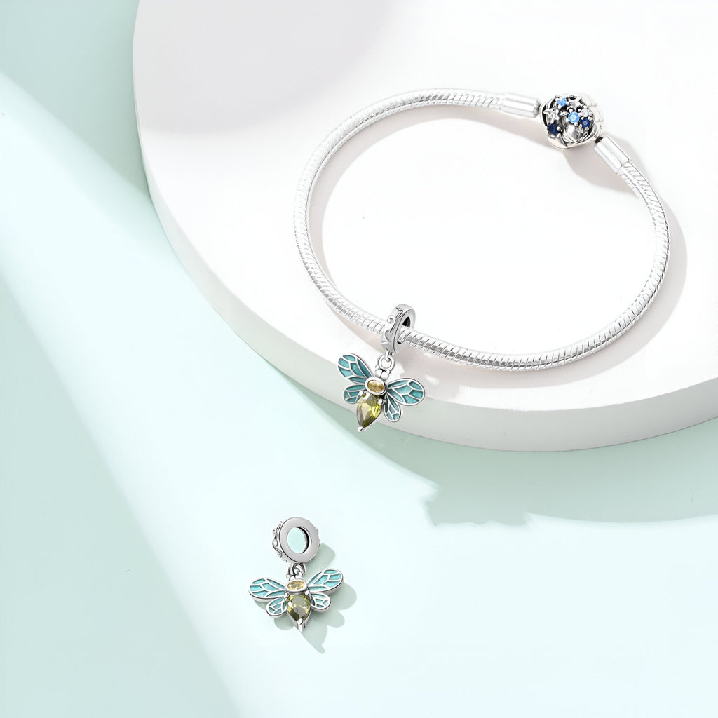 Charm pendent abeille argent avec ailes turquoise et détail doré sur bracelet argenté.