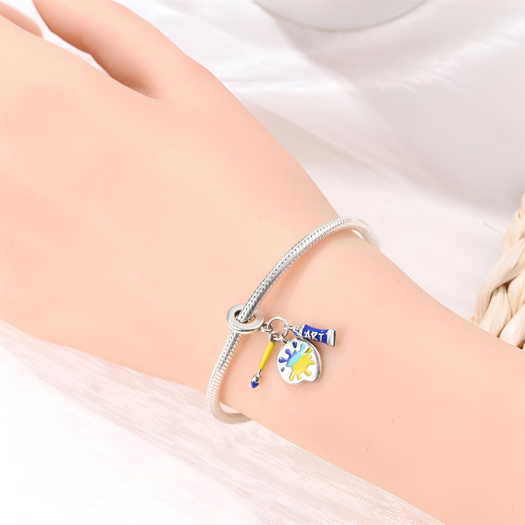 Bracelet argenté avec pendentifs miniature palette de peinture et pinceau colorés.