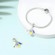 Bracelet argenté avec pendentif charm peint en blanc, jaune et bleu, motif artistique.