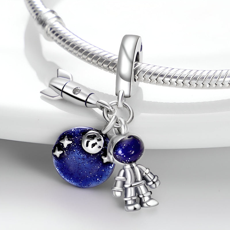 Charm pendentif modèle Phaedra en argent avec globe bleu étoilé et petite figurine astronaute suspendue.