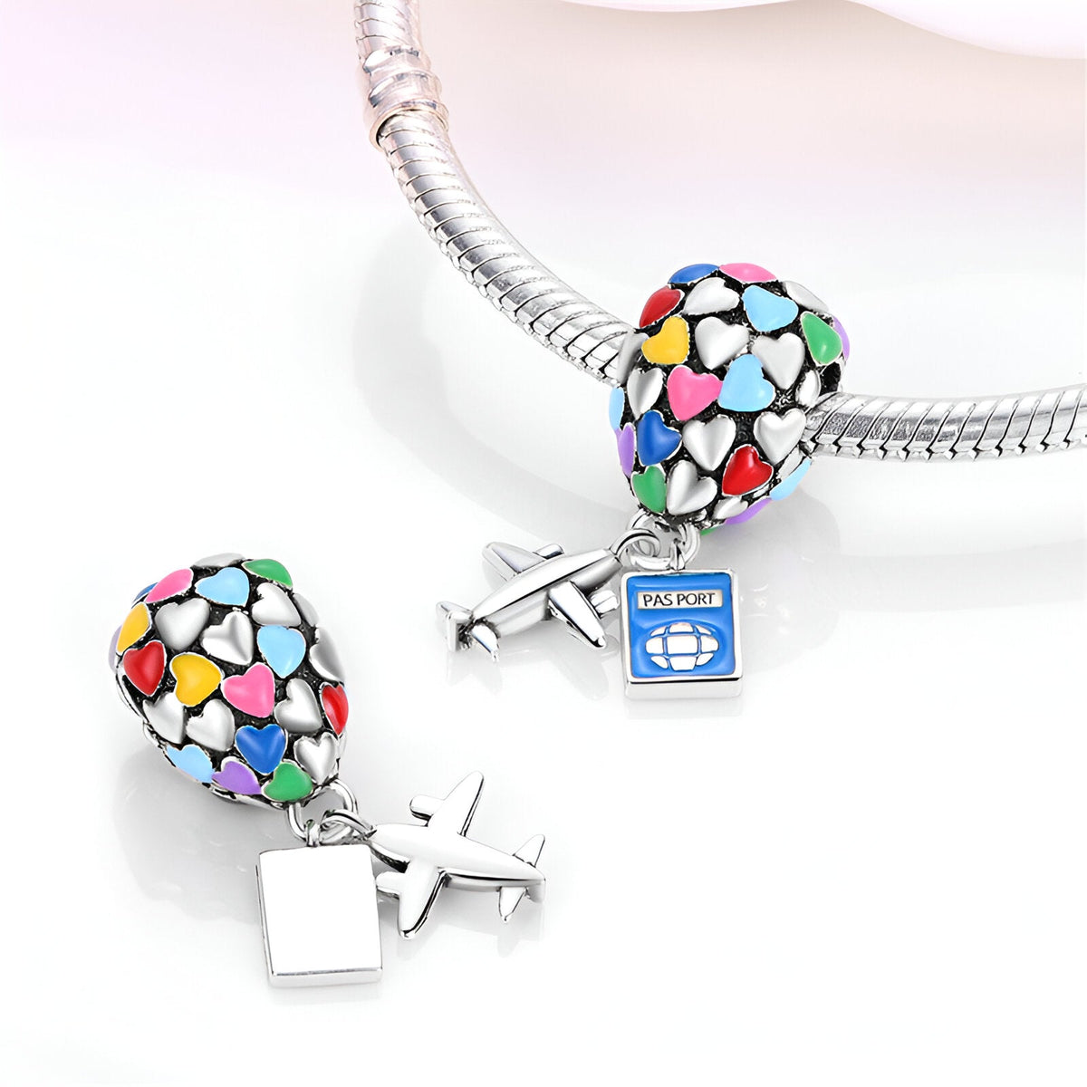 Charm pendentif en forme de montgolfière multicolore et avion argenté sur bracelet serpent.