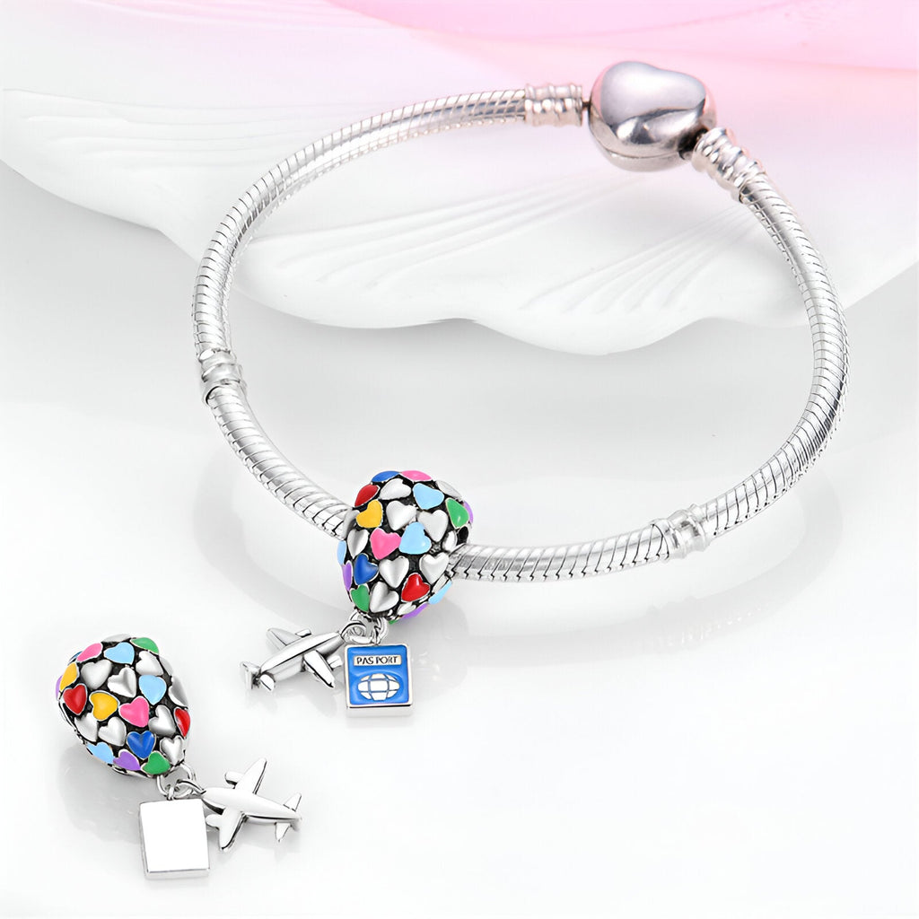 Bracelet argenté avec pendentif cœur multicolore et charme avion bleu en métal.