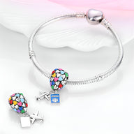Bracelet argenté avec pendentif cœur multicolore et charme avion bleu en métal.