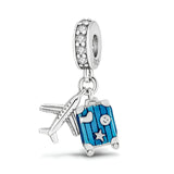Charm pendentif argent avion et valise bleue à rayures avec étoiles et cristaux blancs.