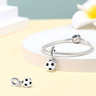 Charm pendentif ballon de foot blanc et noir en émail, attaché à un bracelet argenté fin.
