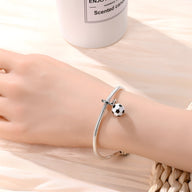 Bracelet argenté avec pendentif en forme de ballon de football noir et blanc.