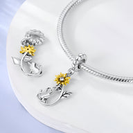 Charm pendentif en argent représentant un chat assis avec un tournesol jaune éclatant.