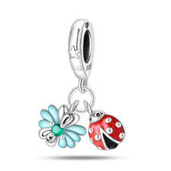 Charm pendentif argent avec coccinelle rouge et feuille bleue émaillée, détails noirs et blancs.