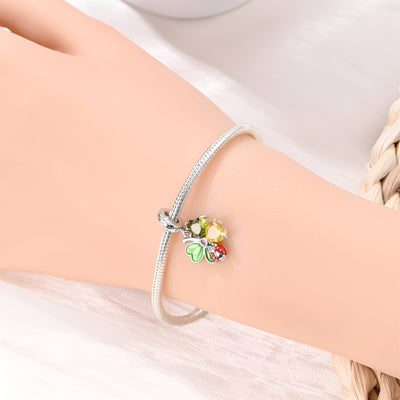 Bracelet argenté avec pendentif coccinelle rouge sur trèfle vert et jaune.