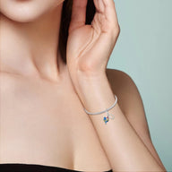 Bracelet fin argenté avec pendentif petit coq rouge et fer à cheval doré.