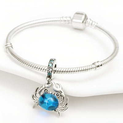 Bracelet argent avec pendentif crabe bleu en verre, style délicat et moderne.