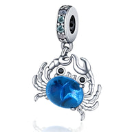 Charm pendentif crabe en argent avec pierre bleue facettée et anneau orné de petits cristaux bleus.