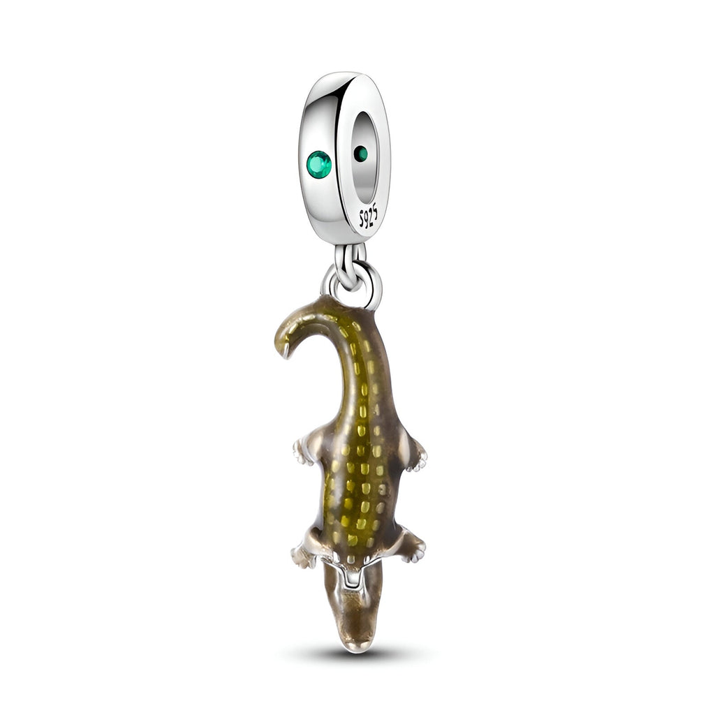 Charm pendentif crocodile en métal argenté avec détails dorés et œil vert émeraude.