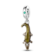 Charm pendentif crocodile en métal argenté avec détails dorés et œil vert émeraude.
