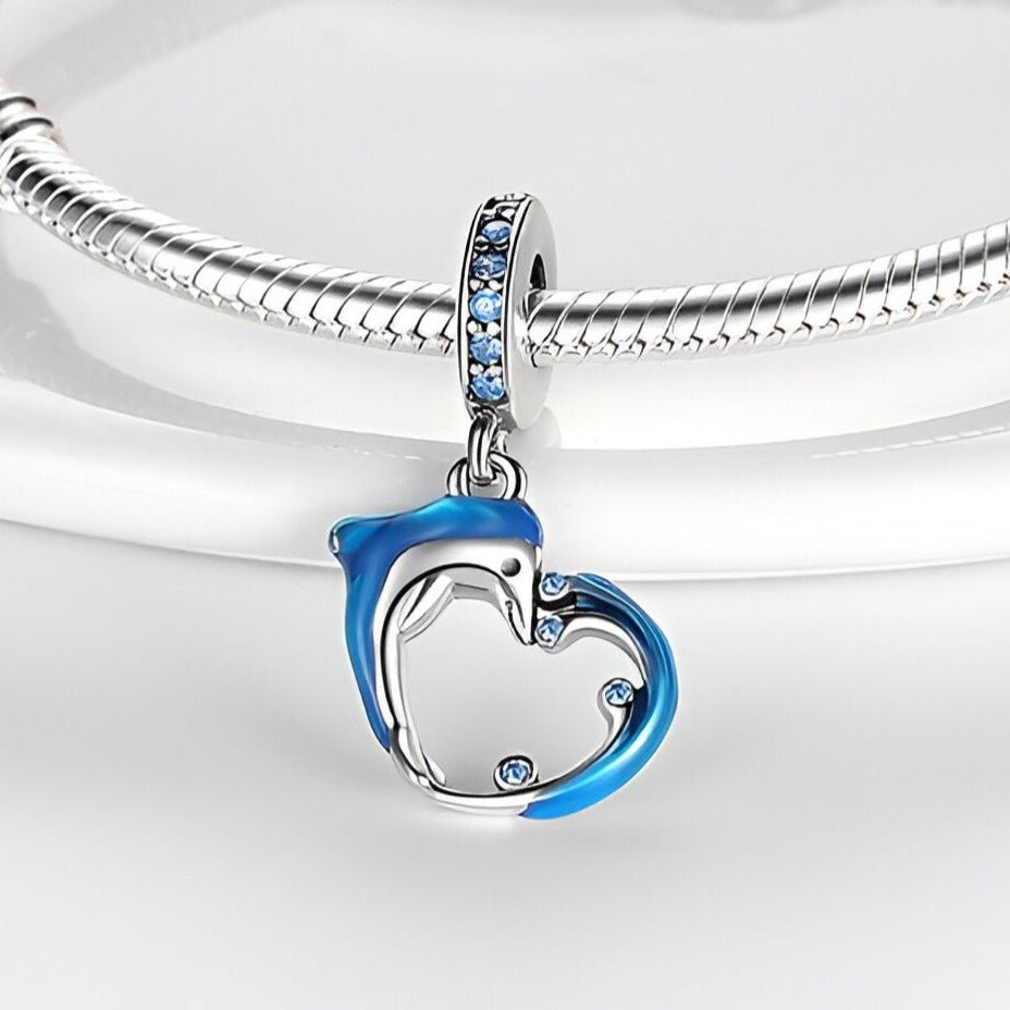 Charm pendentif dauphin et vague en acier avec détails bleus et strass sur anneau, style élégant.