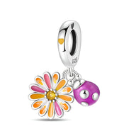 Pendentif charm en argent avec marguerite orange et rose et coccinelle violette à pois blancs.