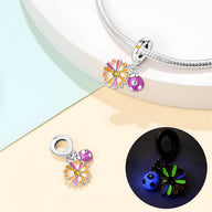 Pendentif charm argent fleur chrysanthème jaune orange et coccinelle rose à pois blancs, détail phosphorescent nocturne.