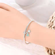 Bracelet argent fin avec pendentif fleur turquoise et breloque ronde gravée.