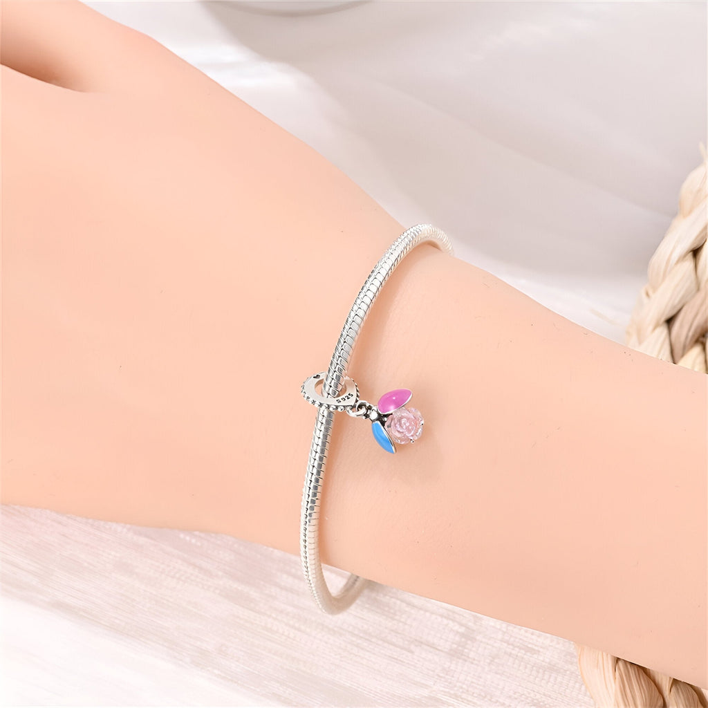 Bracelet argent fin avec pendentif luciole scintillante rose et ailes bleues.