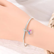 Bracelet argent fin avec pendentif luciole scintillante rose et ailes bleues.