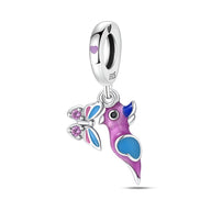 Charm pendentif en argent oiseau violet et bleu avec papillon orné de pierres roses.