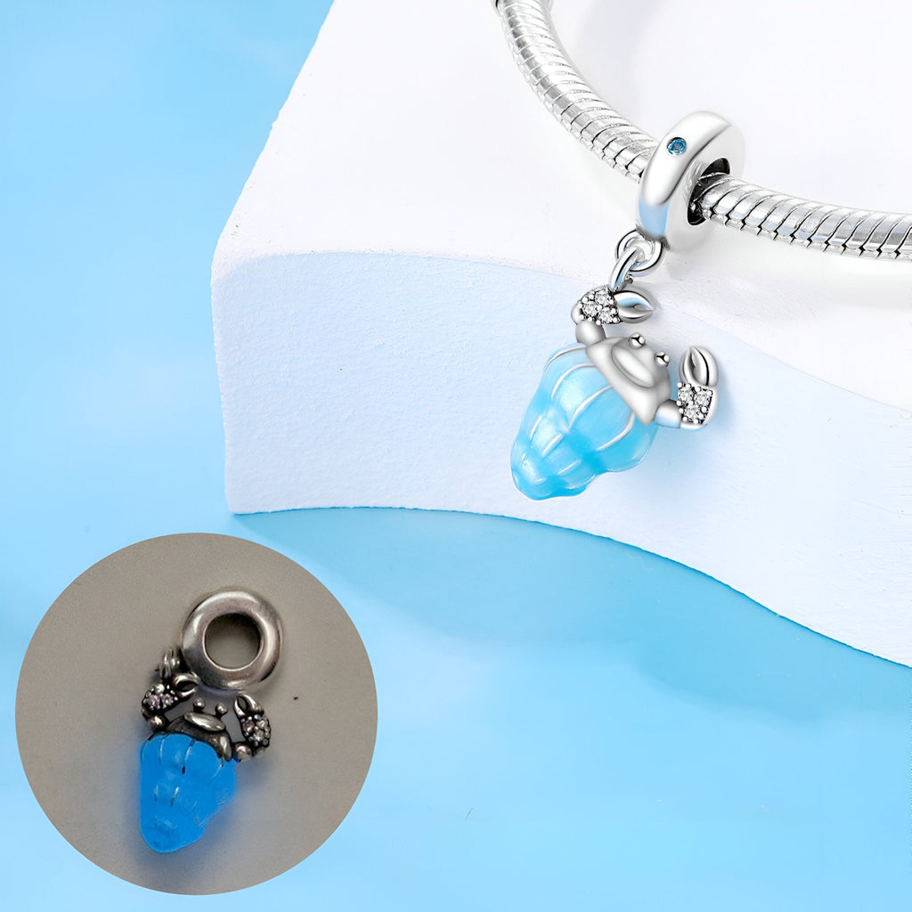 Pendentif charme pagure bleu en argent avec coquillage turquoise scintillant.