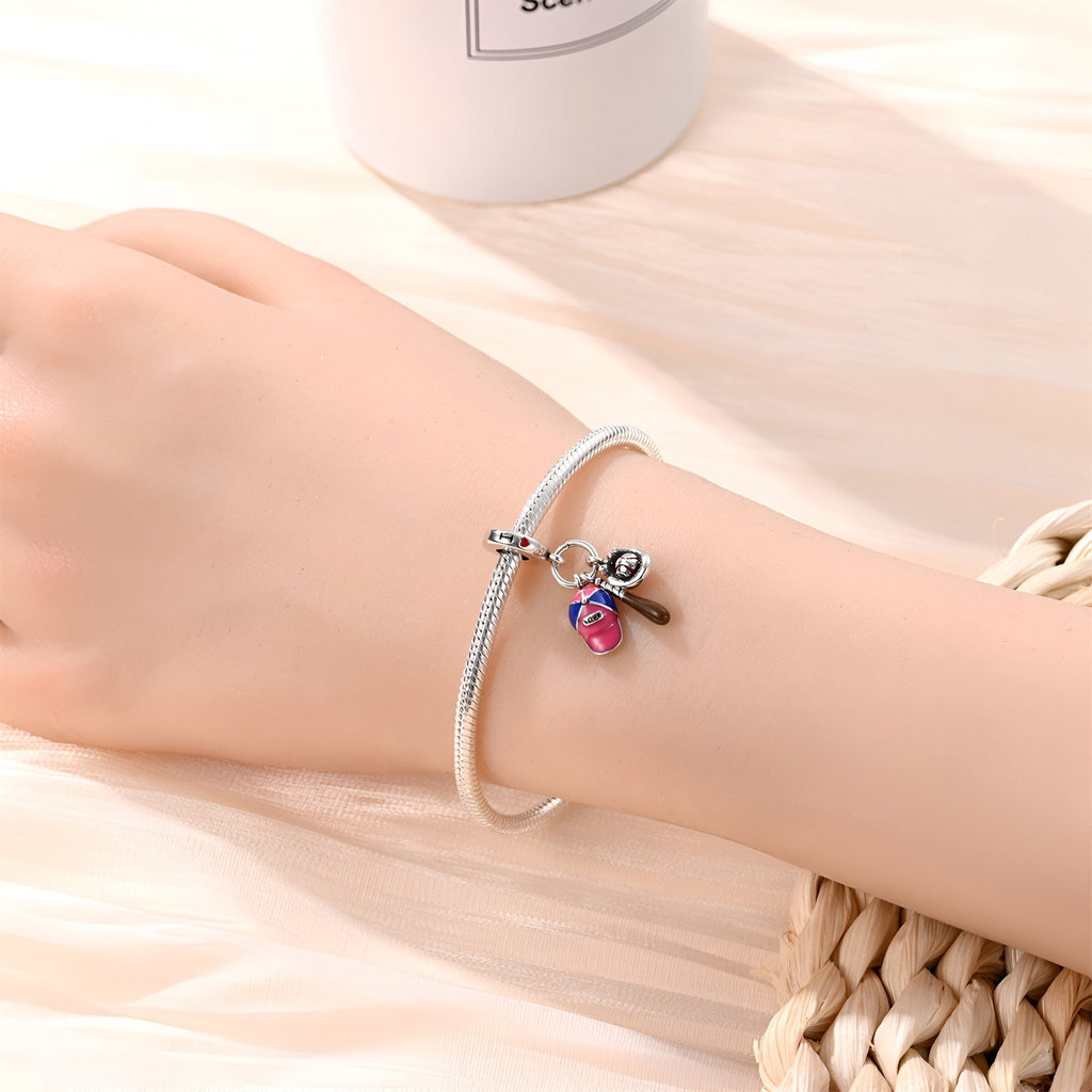 Bracelet argenté fin avec pendentif baseball rose et gant détaillé sur poignet féminin.