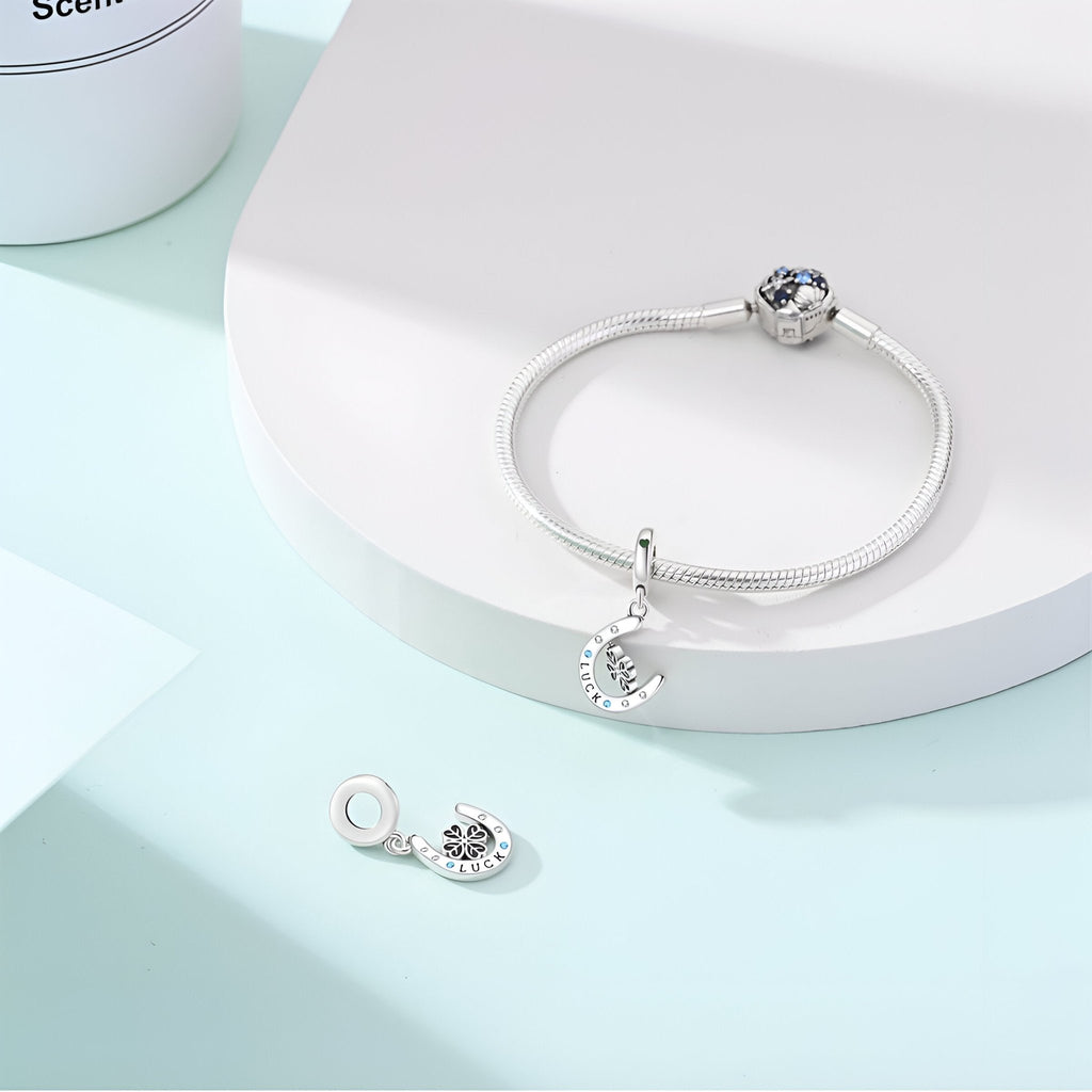 Bracelet argent avec pendentif fer à cheval et trèfle serti de pierres bleues et blanches.