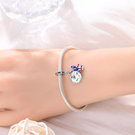 Bracelet argenté fin avec pendentif rond drapeau américain et étoile bleue sur poignet féminin.