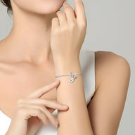 Bracelet fin argenté avec charm pendentif guitare délicat porté au poignet féminin.