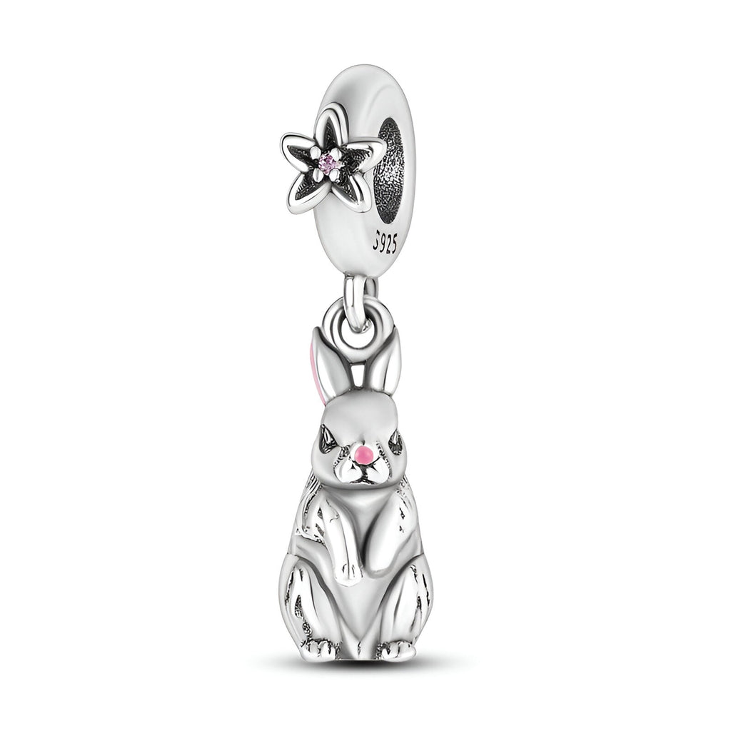 Charm pendentif lapin assis en argent avec détails roses et fleur ajourée sur l’anneau.