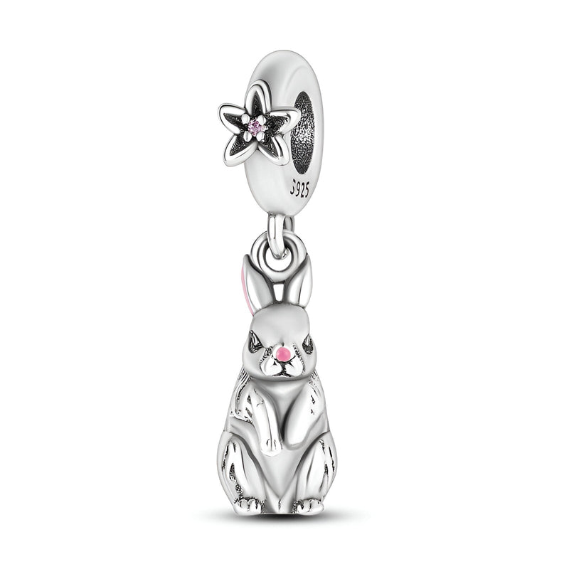 Charm pendentif lapin assis en argent avec détails roses et fleur ajourée sur l’anneau.