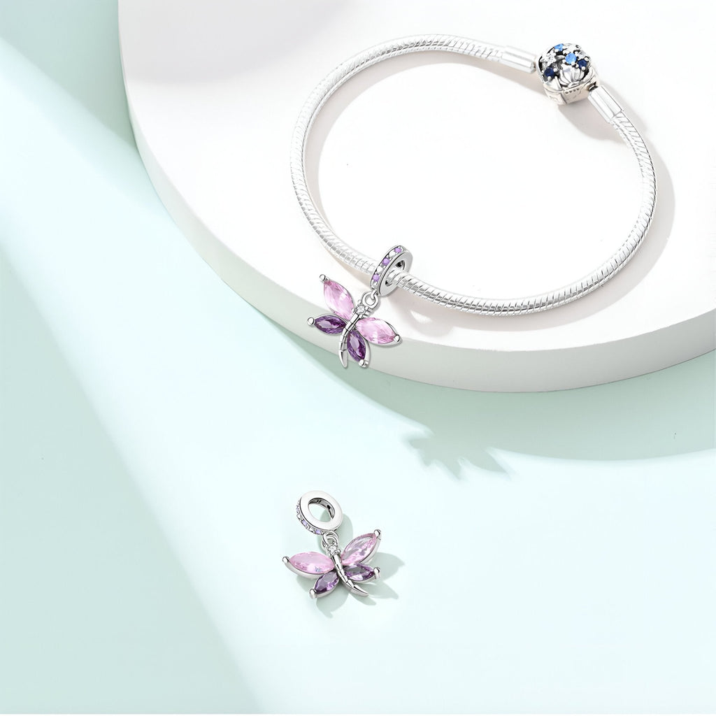 Bracelet argenté avec pendentif libellule rosée violet orné de cristaux colorés et fermoir à bille bleu.